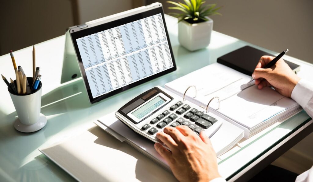 Calculating costs with calculator and laptop.
