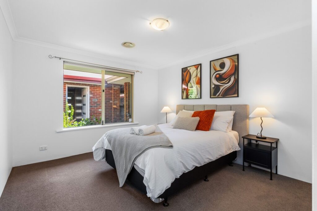 The guest room with a queen bed, along with two bedside tables and two bedside lamps.
