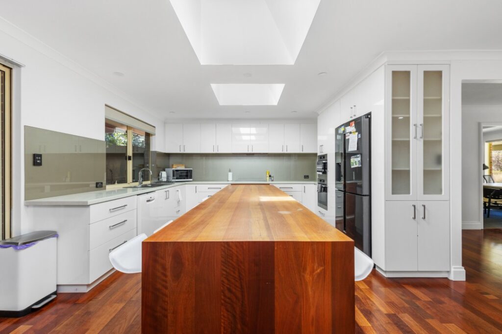 A long kitchen island with a very spacious kitchen area, along with an oven, microwave, and electric kettle.