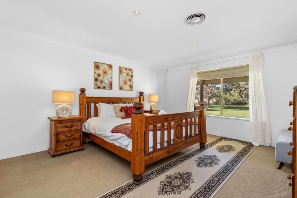 The master bedroom with a king bed, along with two bedside tables, two bedside lamps, a TV, and an ensuite bathroom.
