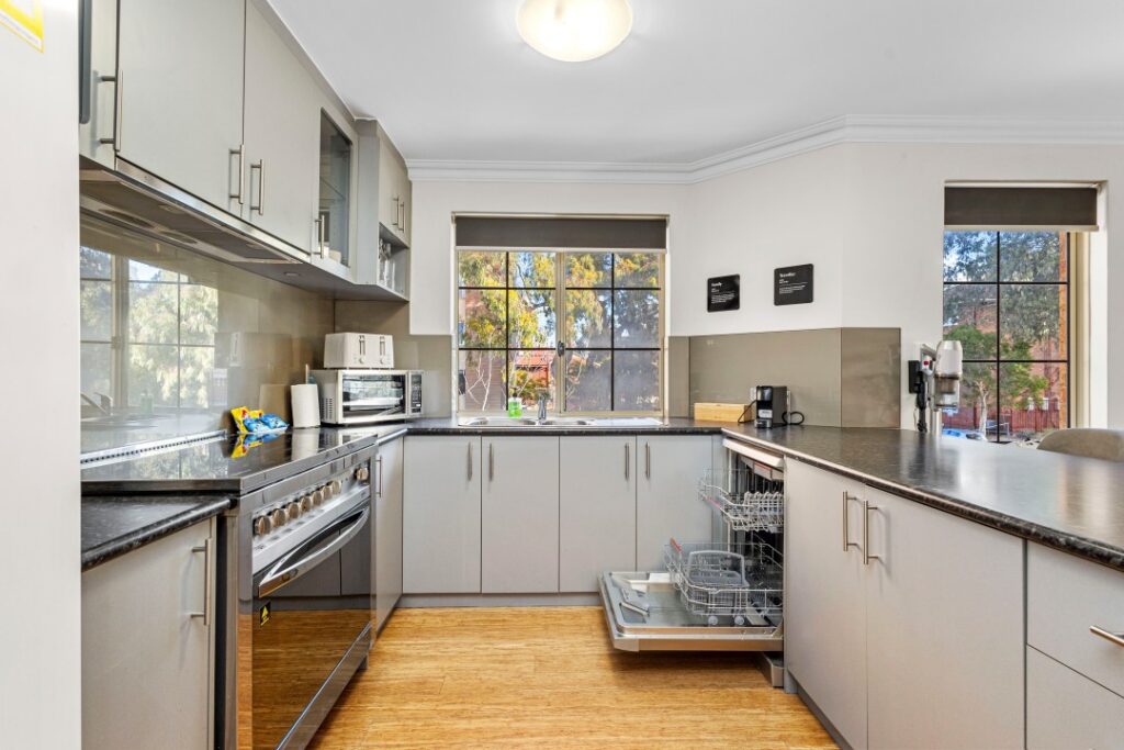 Modern kitchen with stove, oven, dishwasher, microwave and coffee machine appliances.