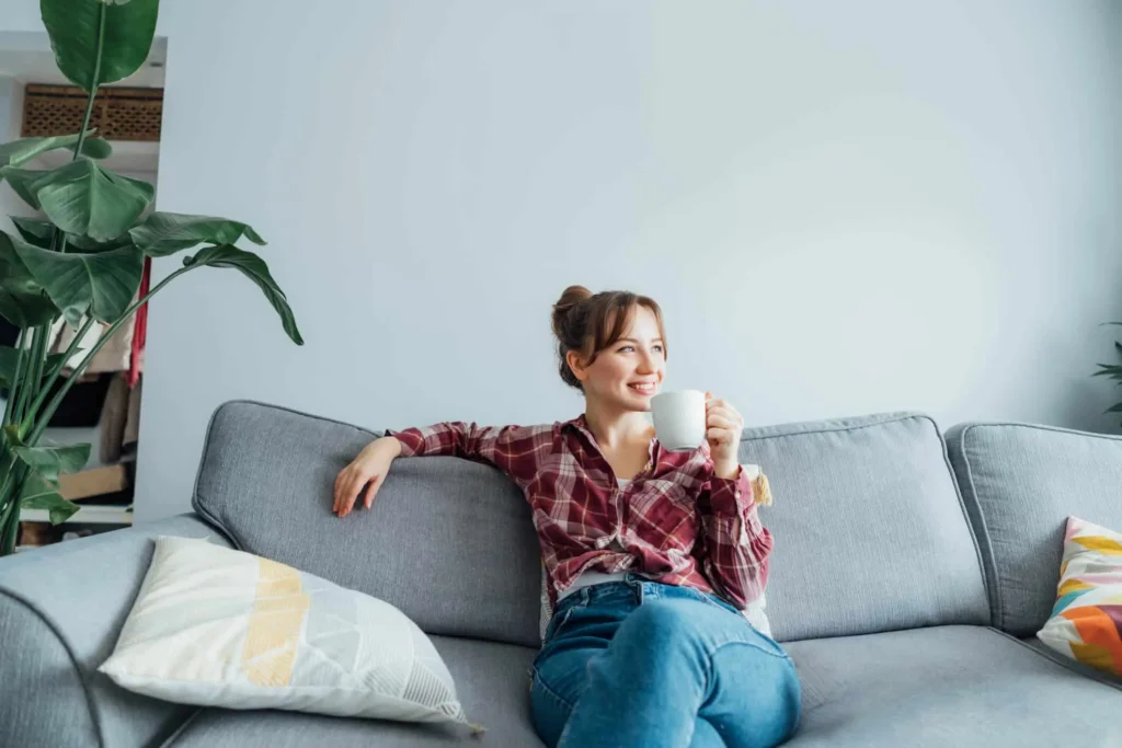 Relaxing woman enjoying a cup on the sofa.