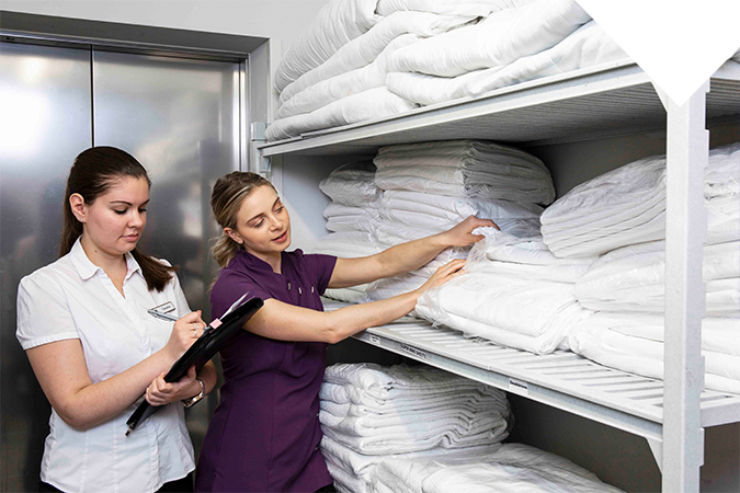 Two women organizing clean linens.
