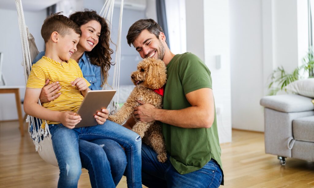 Happy family with modern devices and dog having fun playing at home