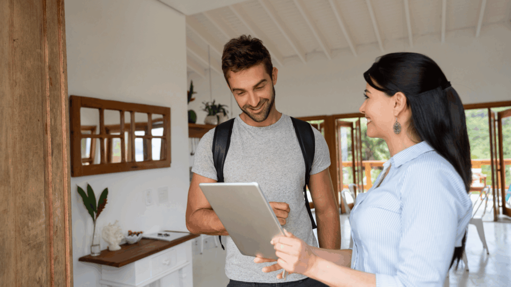 The man and woman smile, and the Airbnb host shows the house rules to the guest
