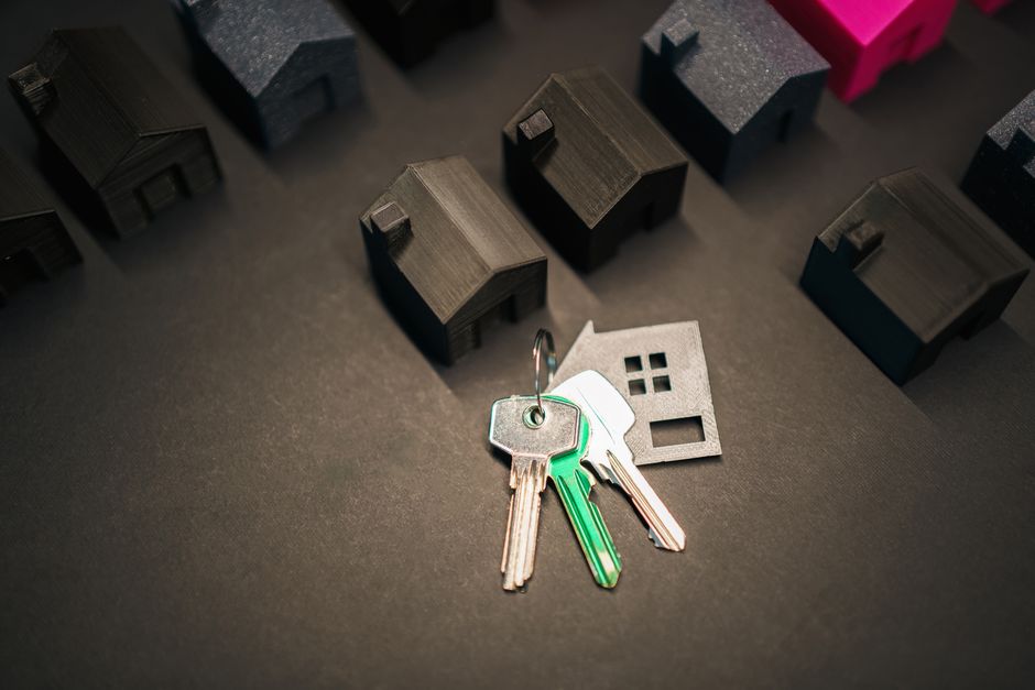 Miniature house models and keys symbolising real estate investment and property decisions.