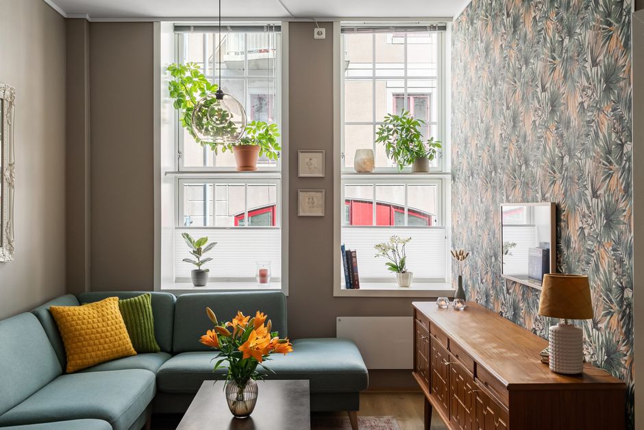 Stylish apartment living room with natural light, plants, and cosy modern decor.