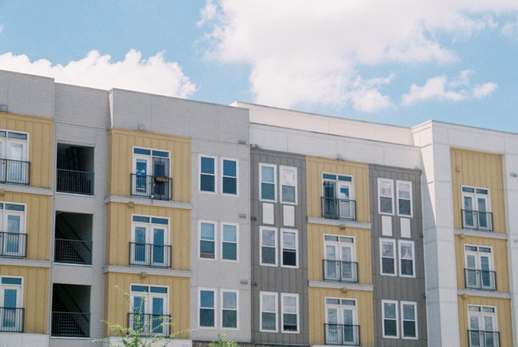Contemporary apartment building exterior with yellow and grey panels under clear blue sky.