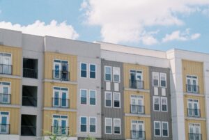 Contemporary apartment building exterior with yellow and grey panels under clear blue sky.