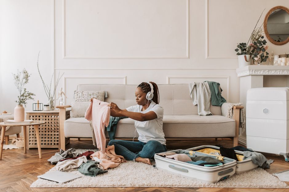 Woman packing suitcase at home with luggage, preparing for holiday travel.