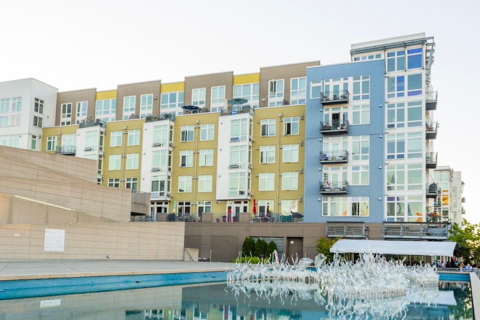 Modern apartment complex with pool and balconies, urban multi-unit building.