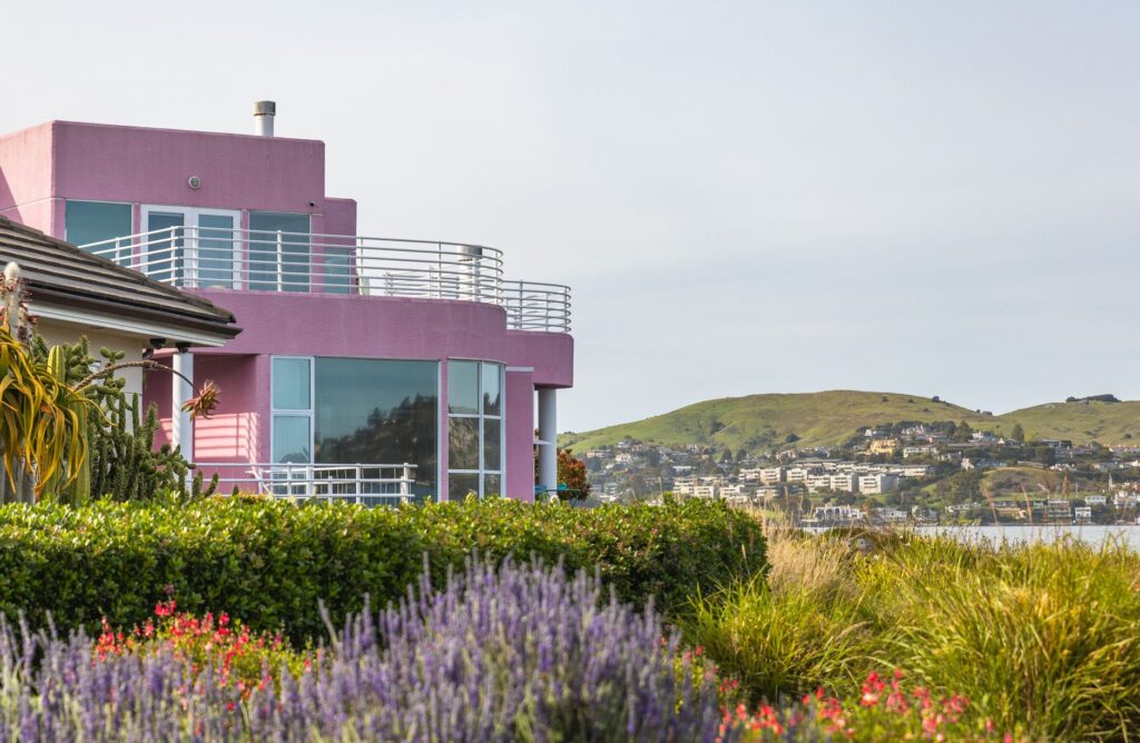 Modern coastal home with balcony overlooking hills and native gardens in summer.