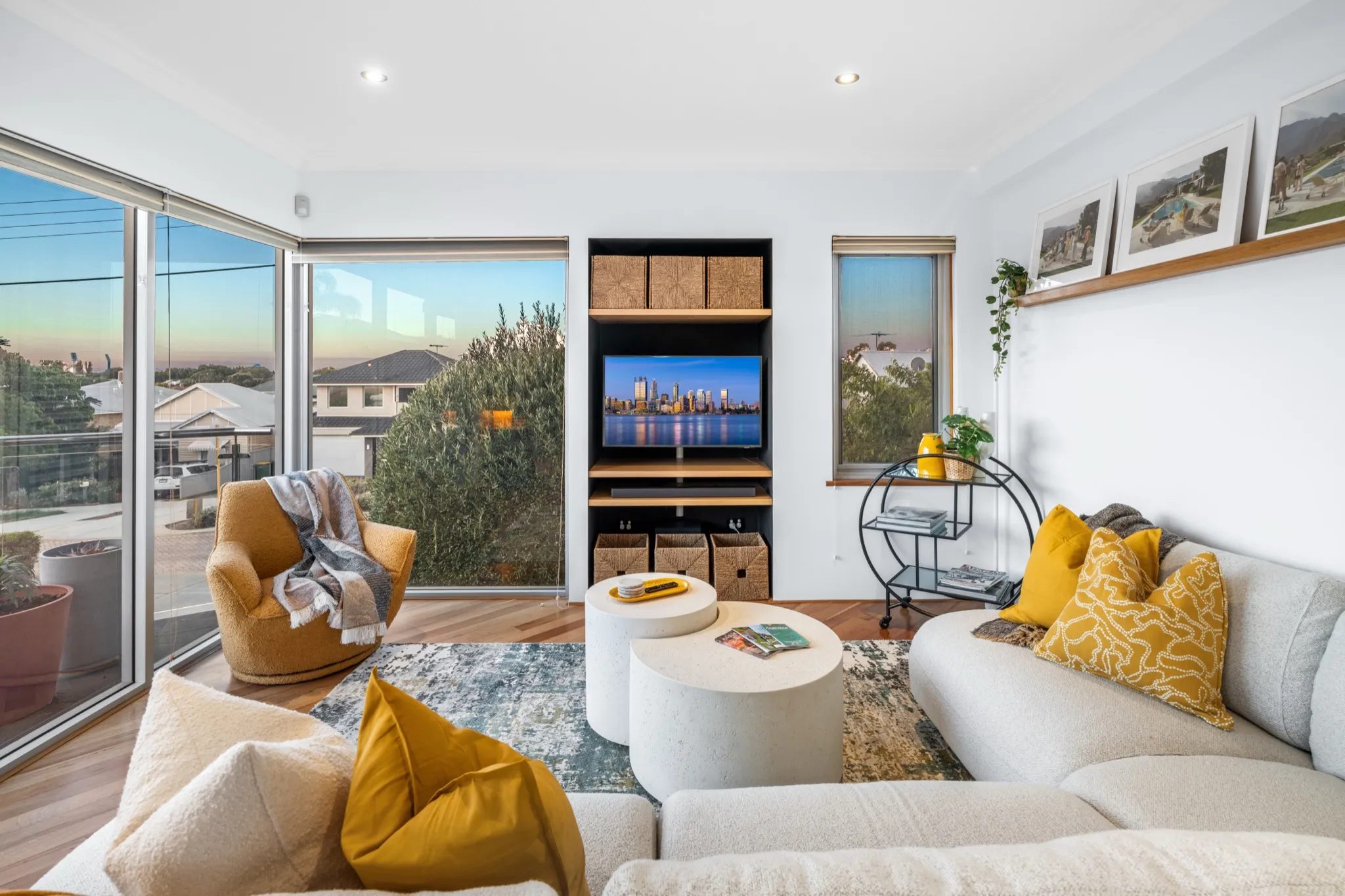 Light-filled living room with grey sofas, yellow cushions and large windows